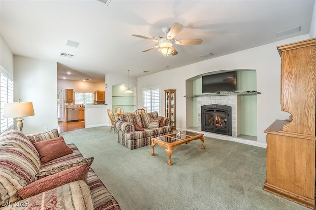 living room with a tile fireplace, carpet flooring, and ceiling fan