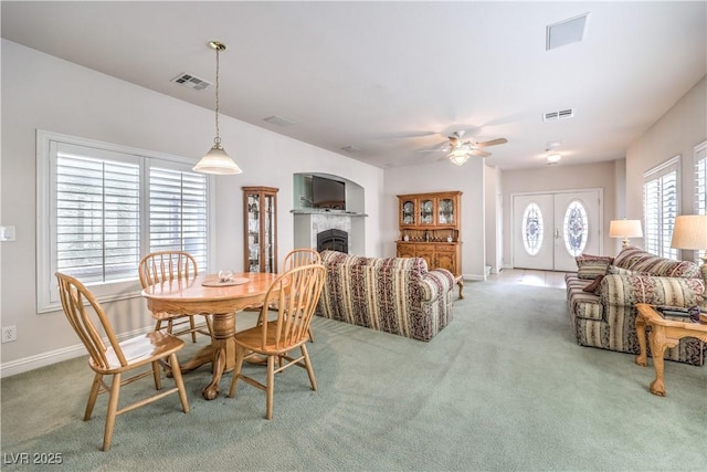 carpeted dining space featuring ceiling fan and a fireplace