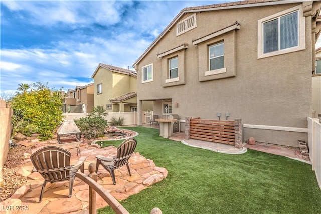 rear view of property featuring a fire pit, a patio area, and a lawn