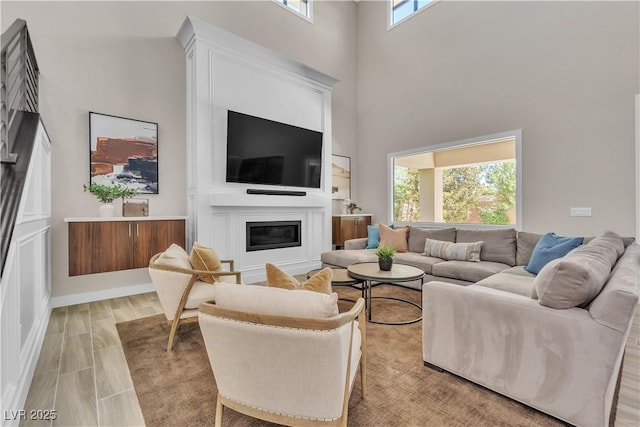 living room with a towering ceiling, a wealth of natural light, and light wood-type flooring