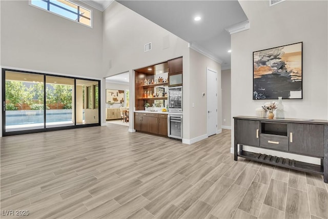 unfurnished living room featuring indoor bar, plenty of natural light, beverage cooler, and light hardwood / wood-style flooring