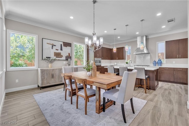 dining space featuring crown molding, light hardwood / wood-style floors, and a chandelier