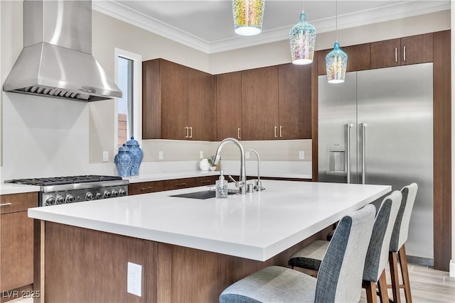 kitchen with decorative light fixtures, a kitchen island with sink, sink, and exhaust hood