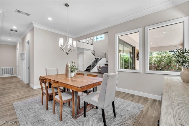 dining room featuring crown molding, a chandelier, a wealth of natural light, and light hardwood / wood-style floors