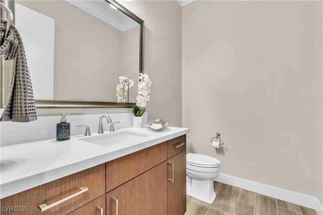 bathroom with vanity, crown molding, and toilet