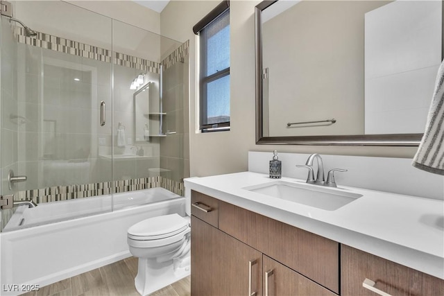 full bathroom featuring vanity, hardwood / wood-style floors, enclosed tub / shower combo, and toilet