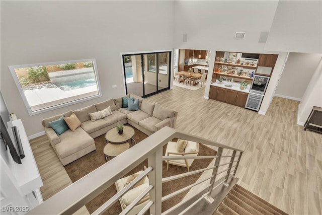 living room featuring a towering ceiling and light hardwood / wood-style floors