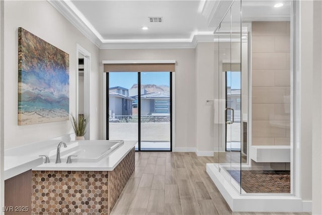 bathroom with ornamental molding, wood-type flooring, and shower with separate bathtub