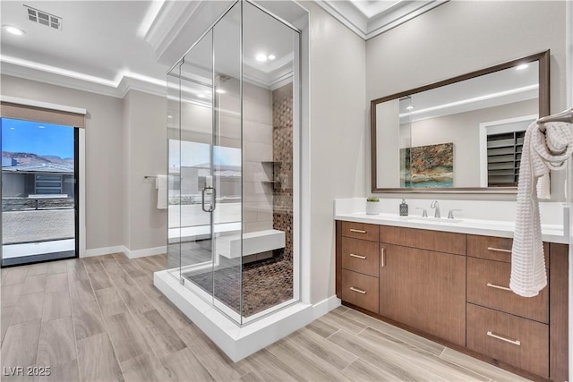 bathroom featuring a shower with door, crown molding, and vanity