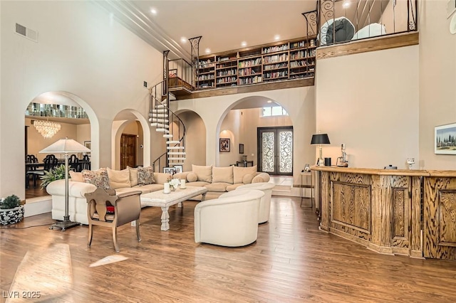 living room with hardwood / wood-style flooring, a towering ceiling, and french doors