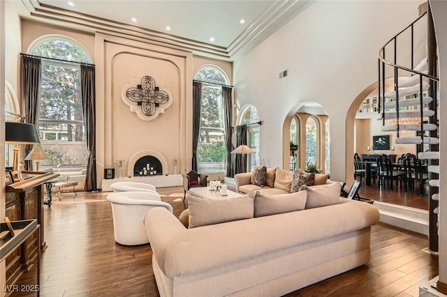 living room featuring dark hardwood / wood-style flooring, crown molding, a fireplace, and a towering ceiling