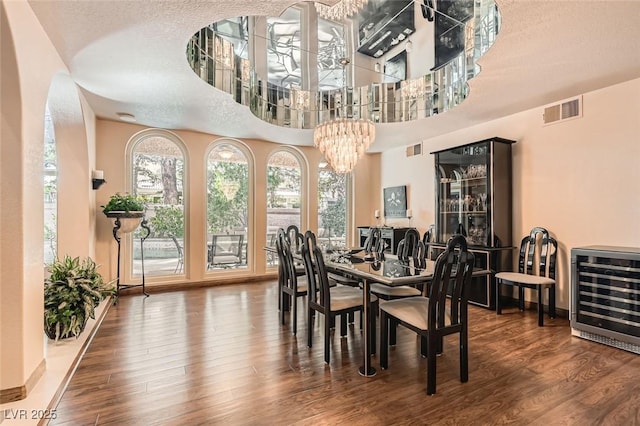 dining room with hardwood / wood-style flooring, beverage cooler, a chandelier, and a textured ceiling