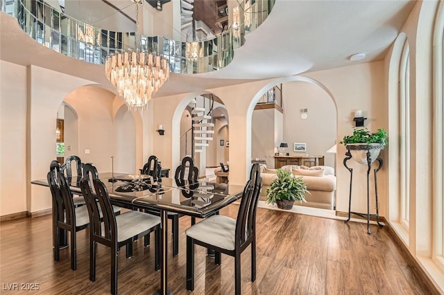 dining space with hardwood / wood-style floors, a towering ceiling, and a notable chandelier