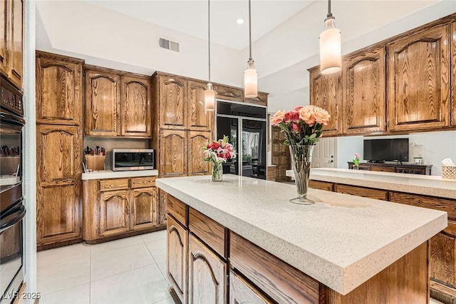 kitchen with light tile patterned flooring, a kitchen island, paneled fridge, and hanging light fixtures