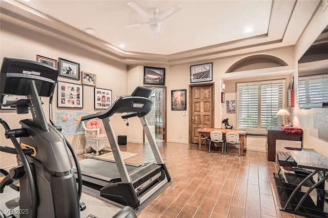 workout area with a raised ceiling, hardwood / wood-style floors, and ceiling fan