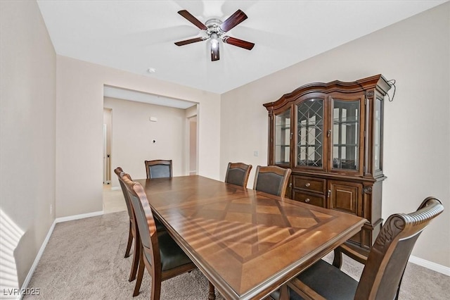 dining area featuring ceiling fan and light carpet