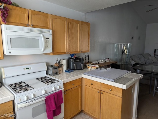 kitchen with tile countertops, white appliances, and kitchen peninsula