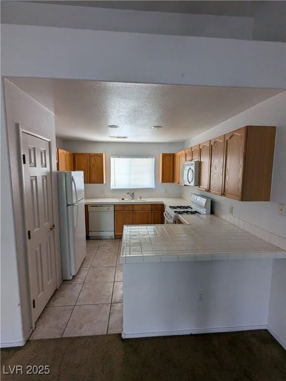 10524 Pine Gardens Ct Unit 203, Las Vegas, NV 89144 - kitchen featuring white appliances, a sink, a peninsula, tile counters, and light tile patterned floors