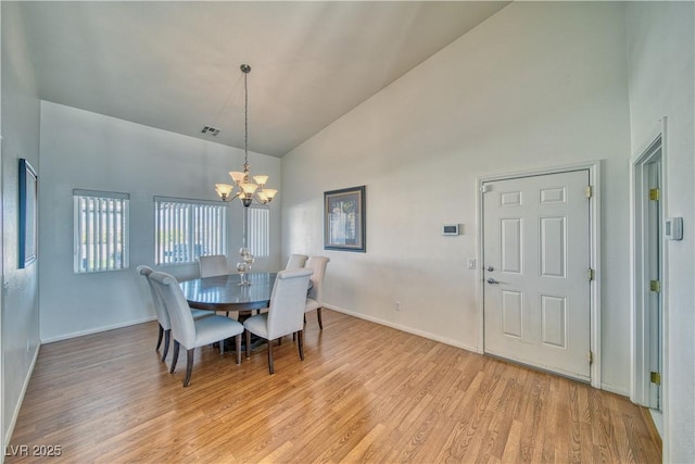 dining space with an inviting chandelier, high vaulted ceiling, and light hardwood / wood-style floors