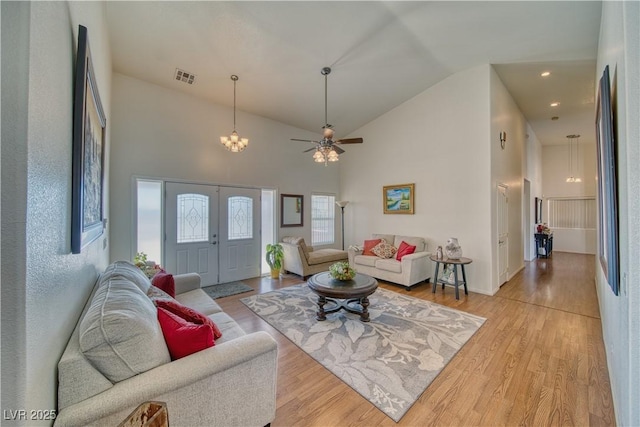 living room featuring high vaulted ceiling, an inviting chandelier, and light wood-type flooring