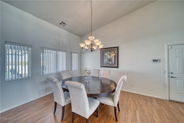 dining room featuring an inviting chandelier, high vaulted ceiling, and light wood-type flooring