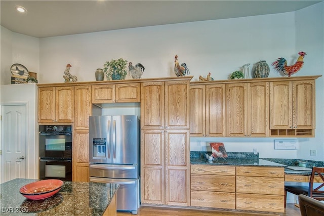 kitchen with stainless steel refrigerator with ice dispenser, black double oven, and dark stone counters