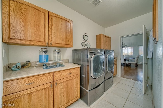 laundry area featuring cabinets, light tile patterned flooring, and washer and dryer