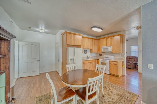 kitchen with light brown cabinetry, white appliances, and light hardwood / wood-style flooring