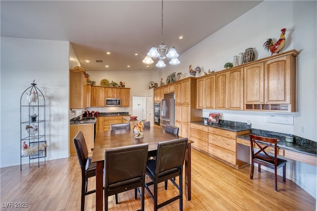 kitchen featuring appliances with stainless steel finishes, decorative light fixtures, sink, a notable chandelier, and light hardwood / wood-style floors