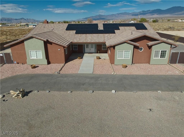 ranch-style home with a mountain view and solar panels