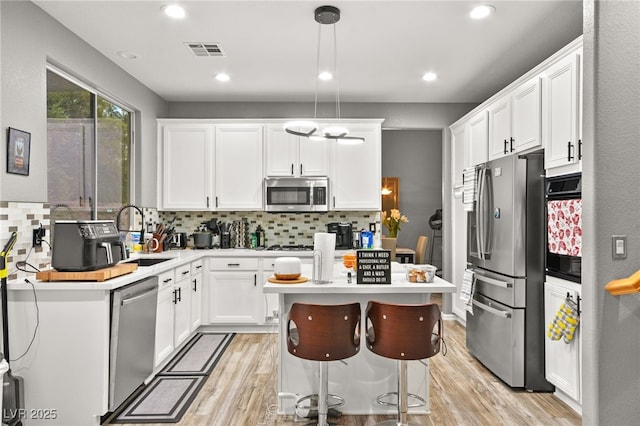 kitchen with appliances with stainless steel finishes, sink, pendant lighting, and white cabinets