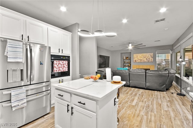 kitchen featuring white cabinetry, stainless steel fridge with ice dispenser, decorative light fixtures, and oven