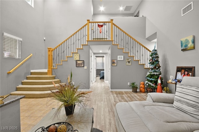 living room with a towering ceiling and light hardwood / wood-style floors