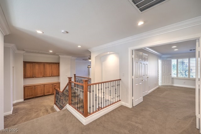 hallway with ornamental molding and light colored carpet