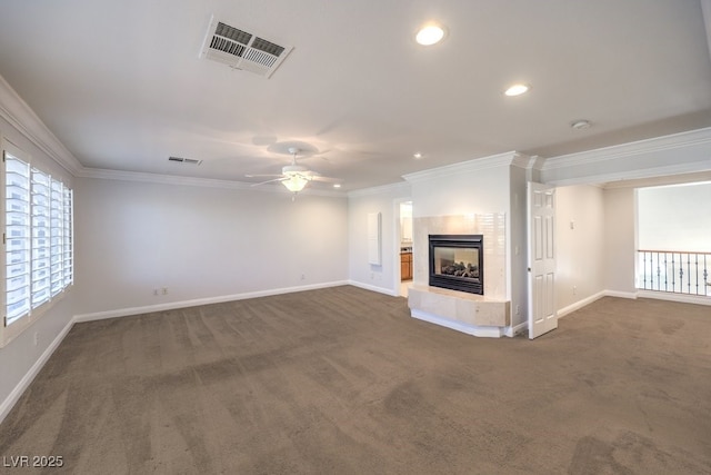 unfurnished living room featuring ceiling fan, ornamental molding, a tile fireplace, and dark colored carpet