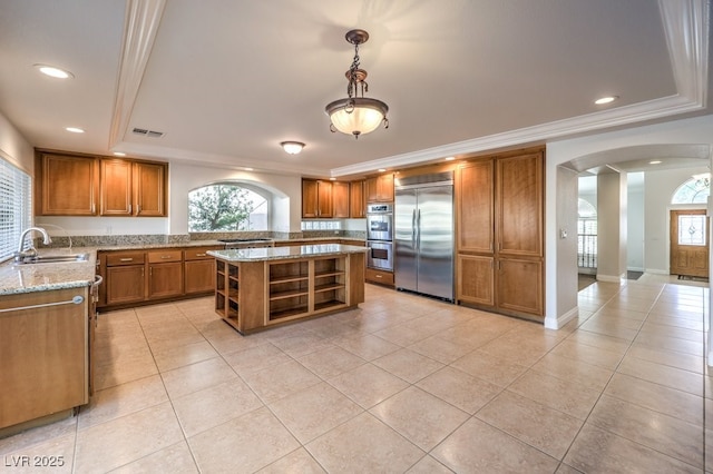 kitchen featuring sink, light tile patterned floors, hanging light fixtures, stainless steel appliances, and a center island