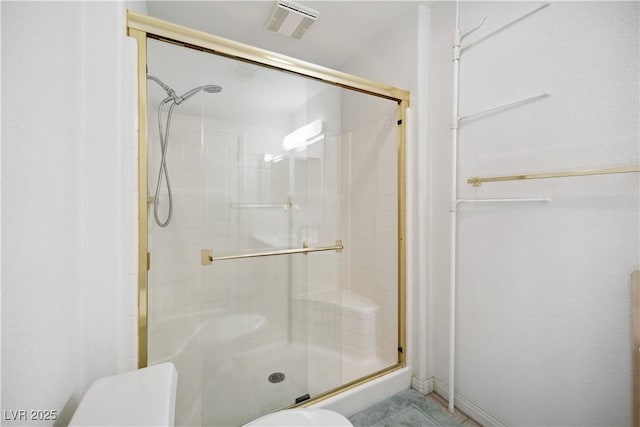 bathroom with a shower with shower door and toilet