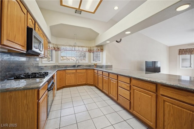 kitchen featuring tasteful backsplash, light tile patterned floors, dark stone countertops, kitchen peninsula, and stainless steel appliances