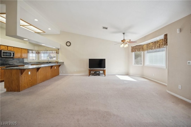 unfurnished living room with sink, light colored carpet, and ceiling fan