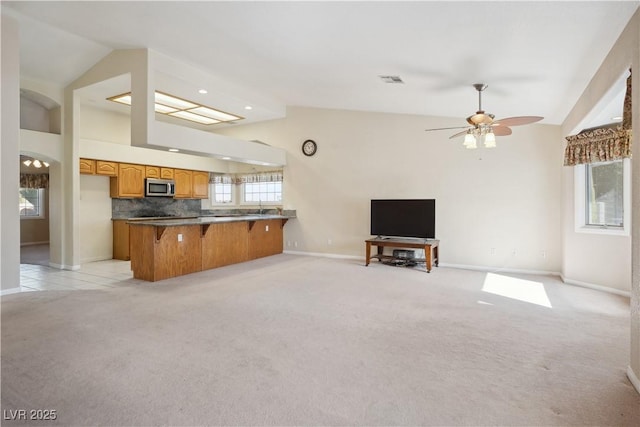 kitchen with lofted ceiling, light colored carpet, kitchen peninsula, and a kitchen bar