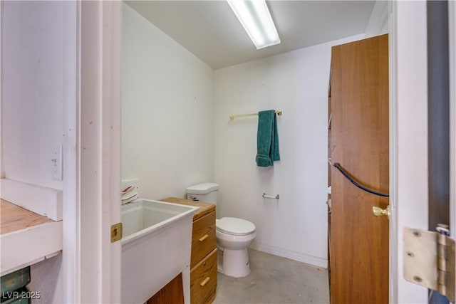 bathroom featuring vanity, concrete flooring, and toilet