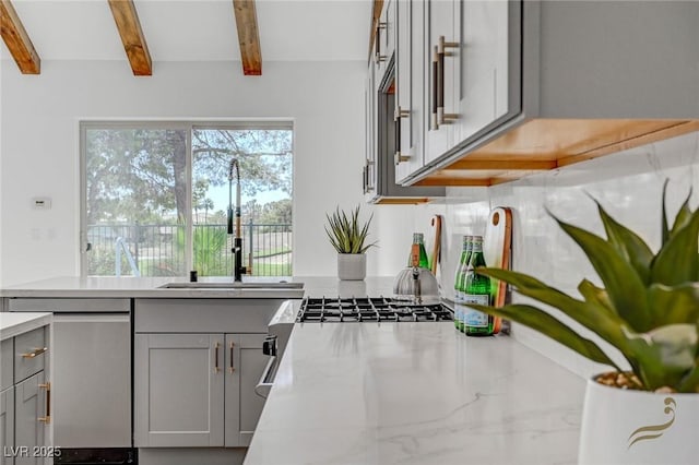 kitchen featuring sink, stainless steel dishwasher, gray cabinets, beam ceiling, and light stone countertops