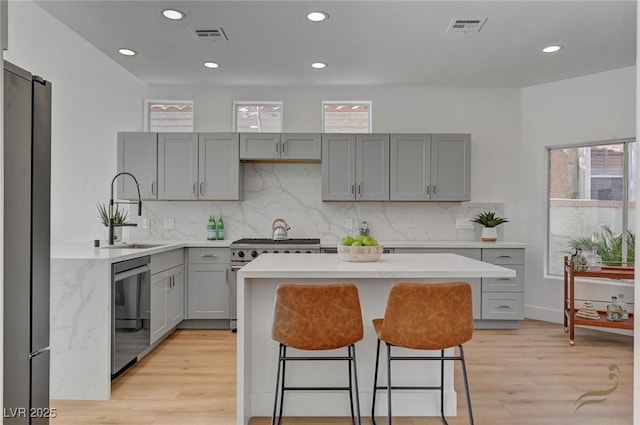 kitchen featuring stainless steel appliances, sink, a kitchen island, and gray cabinetry