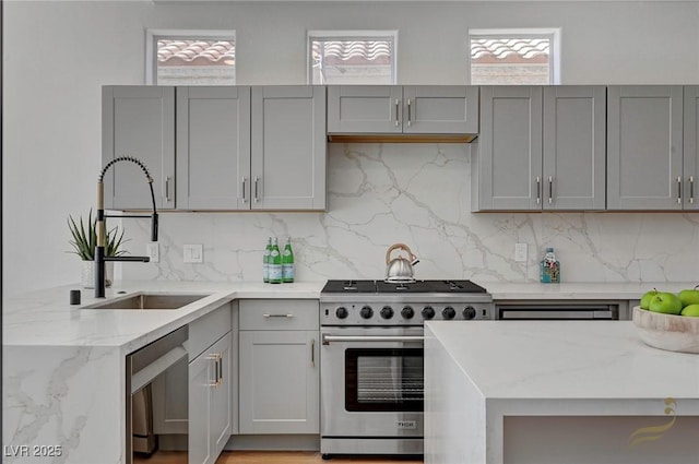 kitchen featuring stainless steel appliances, light stone countertops, gray cabinets, and sink