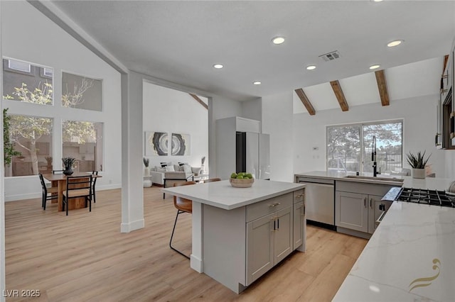 kitchen with gray cabinets, dishwasher, sink, light hardwood / wood-style floors, and light stone countertops