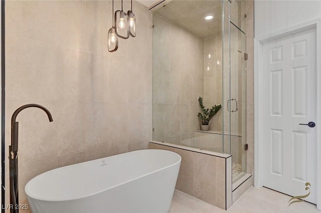 bathroom with tile patterned floors, separate shower and tub, and tile walls