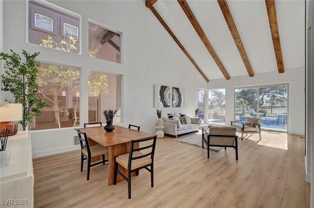 dining room with beam ceiling, high vaulted ceiling, and light wood-type flooring