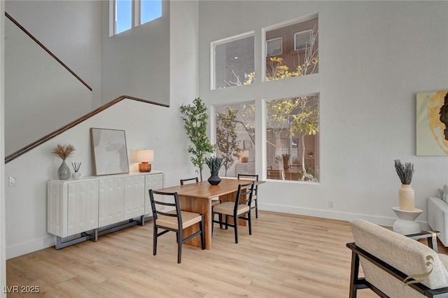 dining space with a towering ceiling, radiator heating unit, and light hardwood / wood-style flooring