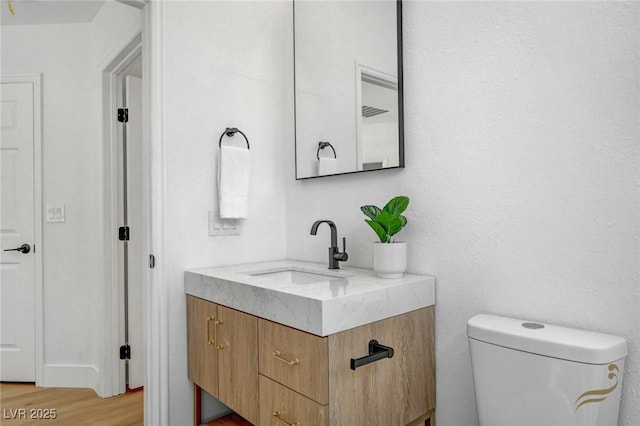 bathroom featuring vanity, hardwood / wood-style flooring, and toilet