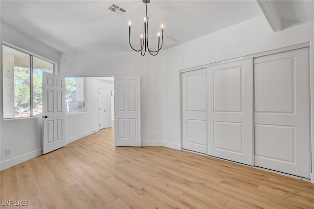 unfurnished dining area with a notable chandelier, beam ceiling, and light hardwood / wood-style flooring